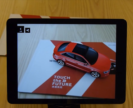 Ein iPad mit aktiver Kamera zeigt auf einen Audi Katalog auf dem ein virtuelles 3d Model eines Audi A3 erscheint. Auf dem Bildschirm sind interaktive Buttons zur Interaktion mit dem AR Model.